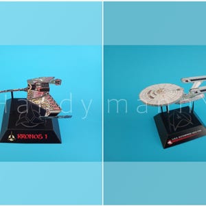 Puede incluir: Dos modelos de naves espaciales de metal sobre bases negras contra un fondo azul. Uno es un modelo Kronos 1 con texto rojo, el otro es un modelo USS Enterprise NCC-1701. Ambos tienen diseños detallados.
