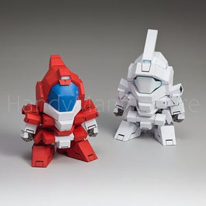 May include: Two robot figurines, one red and white, the other white. The red robot has a blue visor and white accents. The white robot has a rectangular head and a similar design. Both are stylized and have a blocky appearance.