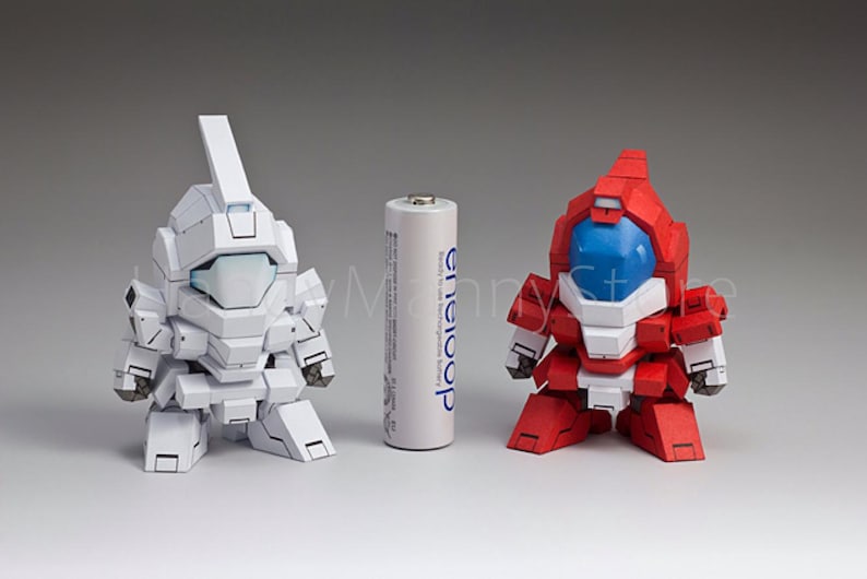 May include: Two robot figurines, one white and one red, stand on a white surface. A standard AA battery is between them. The white robot has a tall, rectangular headpiece. The red robot has a blue visor.