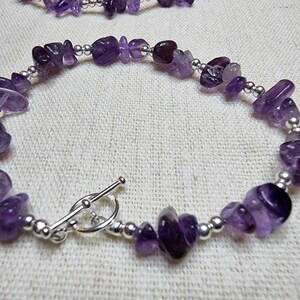 May include: A purple amethyst gemstone bracelet with silver beads and a toggle clasp.