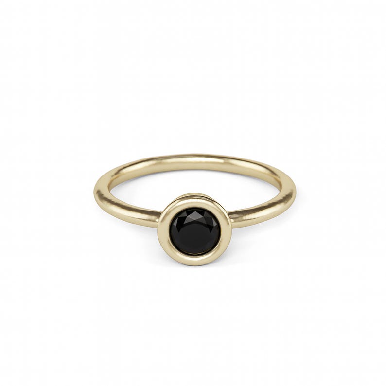 A gold ring with a black gemstone in the center.