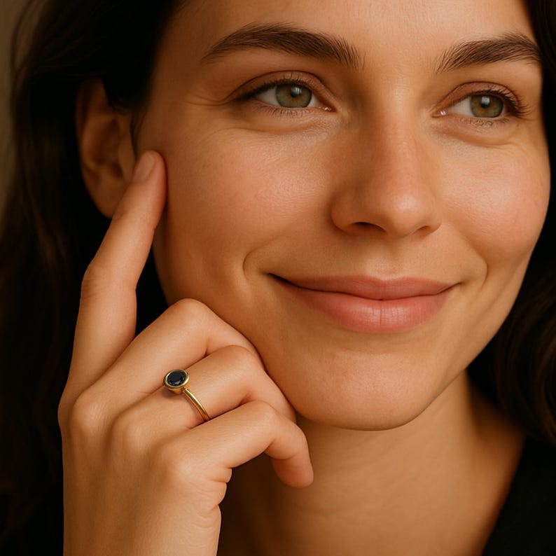 A close-up portrait of a woman with a thoughtful expression, wearing a ring on her finger.