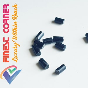 Puede incluir: Primer plano de un montón de palitos negros de iniciador de fuego sobre una superficie blanca.