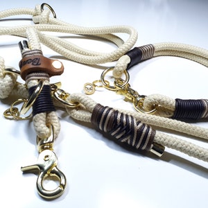 May include: A white and brown rope dog collar and leash set with gold hardware. The leash has a leather tag with the word "Bear" on it.