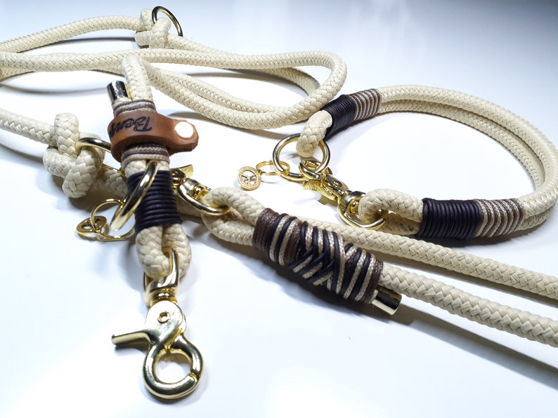 May include: A white and brown rope dog collar and leash set with gold hardware. The leash has a leather tag with the word "Bear" on it.