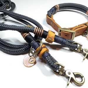 以下が含まれることがあります： 黒とネイビーのロープ製の犬用リードとカラーのセット。茶色の革のアクセントと平和のシンボルのチャームが付いています。