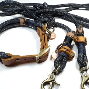 以下が含まれることがあります： 黒と茶色の革製の犬用首輪とリードのセット。リードはネイビーブルーのロープと真鍮製の留め具が付いています。首輪は真鍮製のバックルとネイビーブルーのロープのアクセントが付いています。
