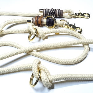 May include: A white rope dog leash with two gold metal clips and two leather wrapped rope ends. One end has the word "Bessel" engraved on it.