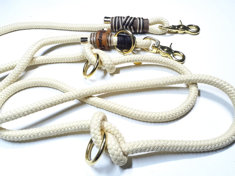 May include: A white rope dog leash with two gold metal clips and two leather wrapped rope ends. One end has the word "Bessel" engraved on it.