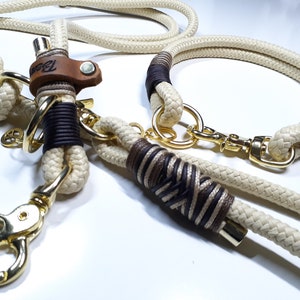 May include: A white and brown rope dog collar and leash set with gold metal hardware. The collar has a brown leather accent with the word "Bark" embossed on it.