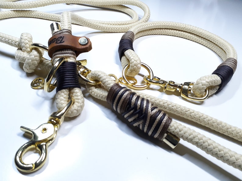 May include: A white and brown rope dog collar and leash set with gold metal hardware. The collar has a brown leather accent with the word "Bark" embossed on it.