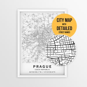 May include: A framed black and white map of Prague, Czech Republic, featuring intricate street networks. Below the map, the text reads PRAGUE, CZECH REPUBLIC, and the coordinates 50°05'00.1"N | 14°24'56.8"E. A circular inset shows a zoomed-in view.