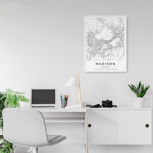 May include: A rectangular wall art print featuring a black and white map of Madison, Wisconsin. The print includes the city name, state, and geographic coordinates 43&deg;04'26.8"N | 89&deg;23'28.9"W printed in black text at the bottom of the map.