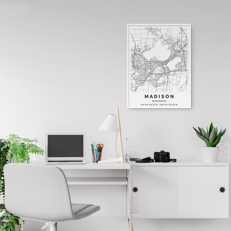 May include: A rectangular wall art print featuring a black and white map of Madison, Wisconsin. The print includes the city name, state, and geographic coordinates 43&deg;04'26.8"N | 89&deg;23'28.9"W printed in black text at the bottom of the map.