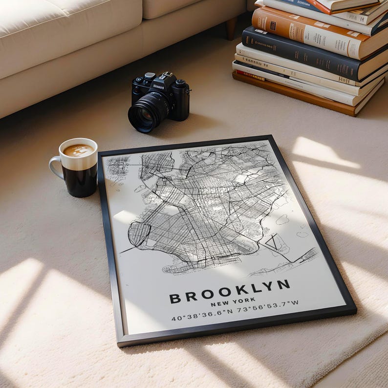 May include: A framed map print of Brooklyn, New York, featuring black street lines on a light background. The text reads BROOKLYN NEW YORK followed by the coordinates 40 38'36.6"N 73 56'53.7"W. The print is displayed in a thin black frame.