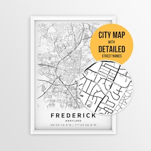 May include: A framed black and white city map of Frederick, Maryland, featuring a circular inset showing detailed street names like Sherman Ave and Catoctin Ave. The text reads FREDERICK MARYLAND 39 25 15.0 N 77 24 58.8 W and CITY MAP WITH DETAILED STREET NAMES.