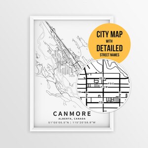 May include: A framed black and white city map of Canmore, Alberta, Canada, featuring street names and coordinates. A circular inset shows a magnified view of the street grid. The text reads CITY MAP WITH DETAILED STREET NAMES.