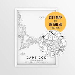 May include: A framed black and white map of Cape Cod, Massachusetts, featuring detailed street lines and coordinates. A circular inset shows a zoomed-in view of local roads including Race Ln and Falmouth Rd, with a yellow badge stating CITY MAP WITH DETAILED STREET NAMES.
