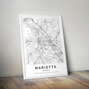 Może przedstawiać: Oprawiony wydruk artystyczny przedstawiający czarno-białą mapę ulic Marietta w stanie Georgia. Wydruk zawiera nazwę miasta, stan oraz wsp&oacute;łrzędne geograficzne 33&deg;57'02.0"N | 84&deg;32'14.4"W zapisane bezszeryfową czcionką u dołu grafiki.