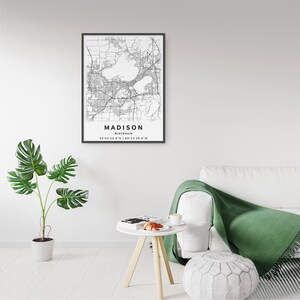 May include: A framed black and white map print of Madison, Wisconsin, featuring detailed street grids and water bodies. The text below the map reads MADISON, WISCONSIN, followed by the geographic coordinates 43&deg;04'25.8"N | 89&deg;23'28.9"W.