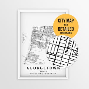 May include: A framed black and white map print of Georgetown, Guyana, featuring a detailed street grid and coordinates. A circular inset highlights specific street names like First St and Second St. A yellow circle contains the text CITY MAP WITH DETAILED STREET NAMES.