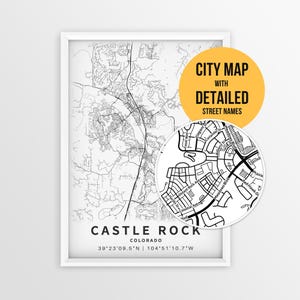 May include: A framed black and white city map of Castle Rock, Colorado, featuring detailed street lines and coordinates. A circular inset shows a magnified view of the street layout with labels like Meadows Blvd and Celestial Ave.