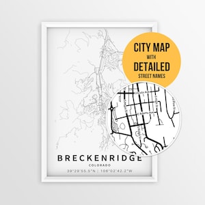 May include: A framed black and white map print of Breckenridge, Colorado, featuring geographic lines and coordinates. A circular inset shows a zoomed-in view of street names including Lincoln Ave, S Main St, S High St, and E Adams Ave.