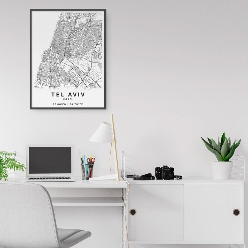 May include: A framed black and white map print of Tel Aviv, Israel. The print includes the city's name, country, and coordinates. The map is detailed, showing streets and urban areas.