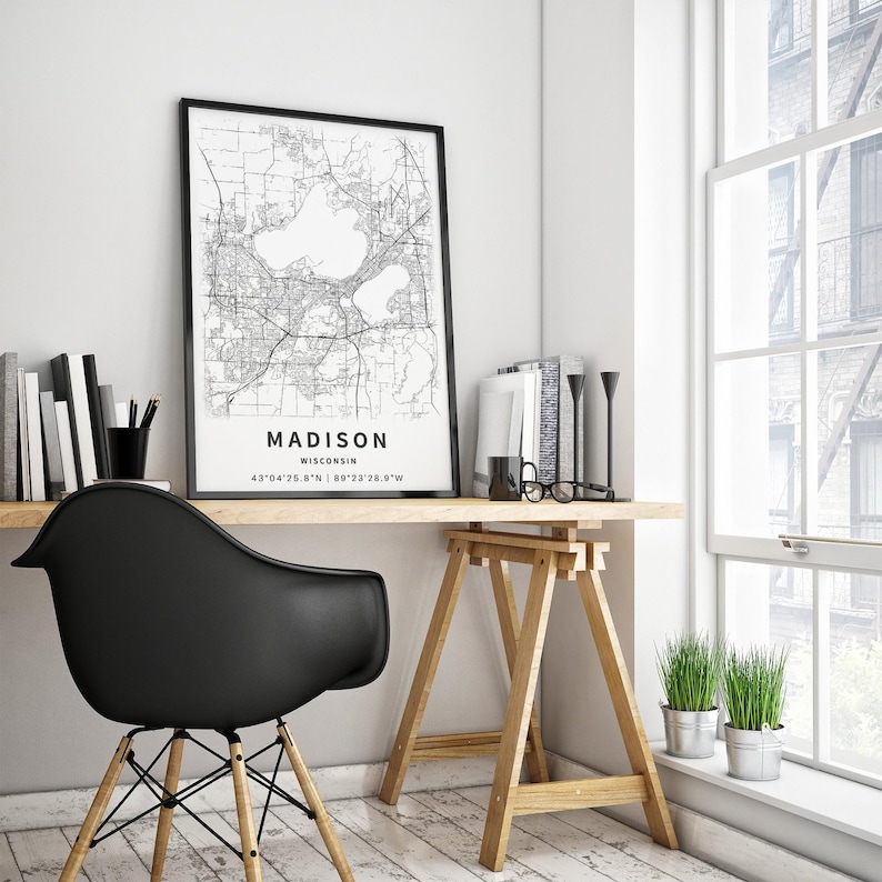 May include: A black and white map print of Madison, Wisconsin, framed in a thin black frame. The map displays city streets and two prominent lakes, with the text MADISON, WISCONSIN, and the coordinates 43&deg;04'25.8"N 89&deg;23'28.9"W printed below.