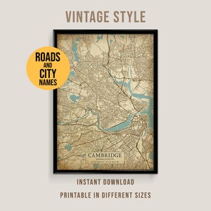 Op de afbeelding: Een ingelijste kaart in vintage-stijl van Cambridge, Massachusetts, met wegen en stadsnamen. De kaart is in bruin- en beigetinten, met blauwe waterelementen. De tekst bevat "Cambridge" en "Direct downloaden, afdrukbaar in verschillende maten."