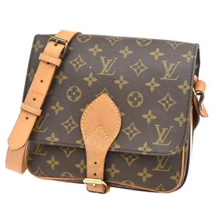 May include: A brown shoulder bag featuring the iconic dark brown and tan monogram pattern. The bag includes a tan leather adjustable shoulder strap and a central tan leather flap closure with a gold-tone metal buckle hardware detail.