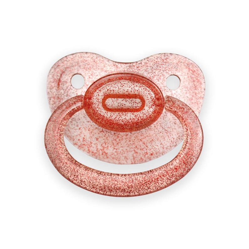 May include: A red glitter pacifier with a clear silicone ring. The pacifier is designed for babies and toddlers.