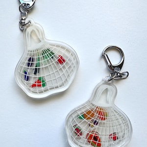 May include: Two clear acrylic keychains shaped like a cage, each with a silver clasp. Inside the cage are colorful, abstract shapes. The keychains are on a white background.