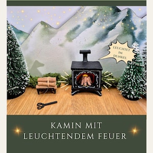 Könnte beinhalten: Ein Miniatur-Kamin in Schwarz mit einem leuchtenden Feuereffekt, vor dem Hintergrund einer Berglandschaft und zwei kleinen Weihnachtsbäumen. Der Text "LEUCHTET IM DUNKEL" befindet sich in einer Sprechblase. Der Text "KAMIN MIT LEUCHTENDEM FEUER" steht unten.