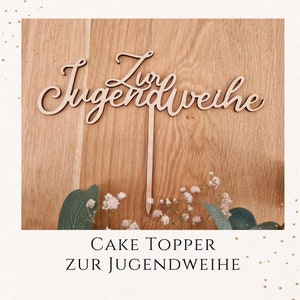 Könnte beinhalten: Holz-Kuchentopper mit dem Text "Zur Jugendweihe" in Schreibschrift. Der Topper befindet sich auf einem Holzgrund mit weißen Blumen.