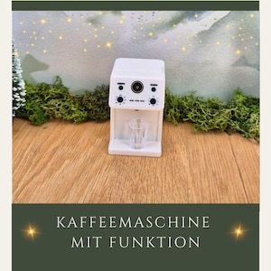 Könnte beinhalten: Eine kleine weiße Kaffeemaschine mit einem durchsichtigen Glas. Die Maschine hat schwarze Knöpfe und Schalter. Der Text "KAFFEEMASCHINE MIT FUNKTION" befindet sich am unteren Rand des Bildes.