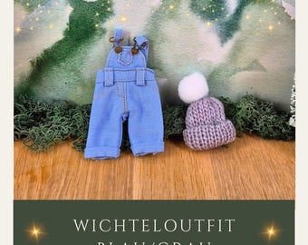 Könnte beinhalten: Ein Miniatur-Jeans-Latzhosen-Set in Blau mit messingfarbenen Verschlüssen und einer passenden Strickmütze in Lavendel mit einem weißen Bommel. Das Outfit wird auf einer Holzoberfläche mit grünem Moos und einem bemalten Hintergrund präsentiert. Der Text "WICHTELOUTFIT BLAU/GRAU" steht unten.