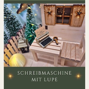 Könnte beinhalten: Miniatur-Schreibmaschine und Lupe auf einem kleinen Holztisch, neben einem Holzstuhl. Die Schreibmaschine hat ein Papier mit Text. Die Szene spielt in einer Miniatur-Außenkulisse mit Zaun, Bäumen und einem kleinen Haus.