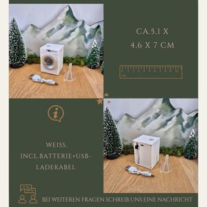 May include: A miniature white washing machine with a USB charging cable and a small funnel. The image includes text that reads "CA.5.1 X 4.6 X 7 CM". The text also includes "WEISS, INCL.BATTERIE+USB-LADEKABEL".