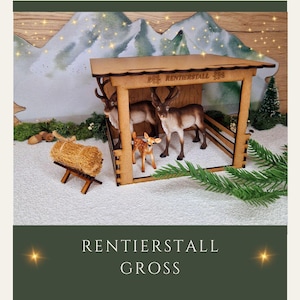 Könnte beinhalten: Ein hölzerner Rentierstall mit braunem Dach und einem Schild mit der Aufschrift "Rentierstall". Im Stall befinden sich drei Rentierfiguren, darunter ein kleines Rehkitz. Der Stall steht auf einer weißen Oberfläche mit einem Heuballen und einem Holzständer.