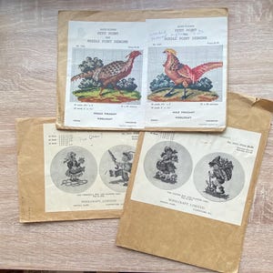 May include: A collection of vintage needlepoint design packets. The packets feature illustrations of pheasants and children. The text on the packets reads "PETIT POINT NEEDLE POINT DESIGNS" and "WOOLCRAFT, LIMITED". The packets are in shades of brown and beige.