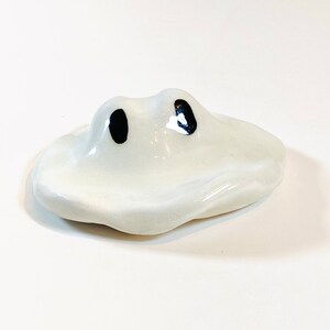 May include: White ceramic chopstick rest shaped like a cloud with two black eyes.