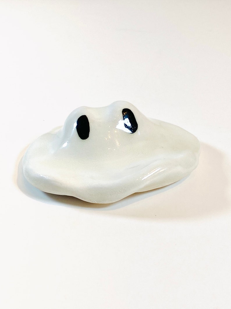 May include: White ceramic chopstick rest shaped like a cloud with two black eyes.
