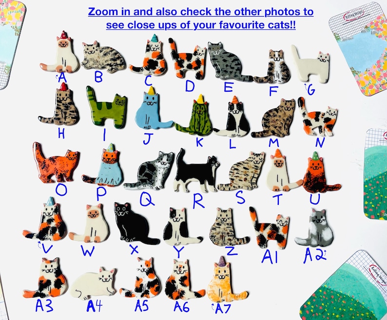 May include: A collection of thirty-four small, flat, ceramic cat-shaped pins or ornaments, each labeled with a letter or alphanumeric code from A to A7. The cats feature various colors, patterns, and some wear small, colorful party hats.