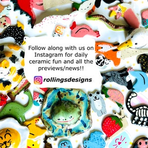 May include: A collection of colorful ceramic figurines, including animals, food items, and abstract shapes. The image includes a frog, a dinosaur, and a strawberry. Text on the image reads "Follow along with us on Instagram for daily ceramic fun and all the previews/news!!" and "rollingsdesigns".