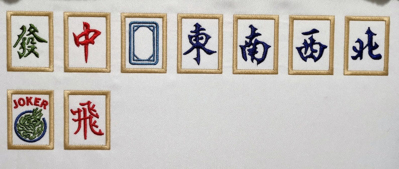 May include: A set of eight mahjong tiles with Chinese characters and a joker tile. The tiles are white with gold trim and the characters are in blue, green, and red.