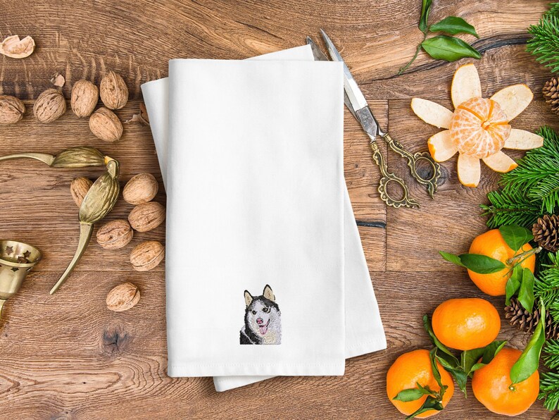 May include: White kitchen towel with a black and white embroidered image of a husky dog.