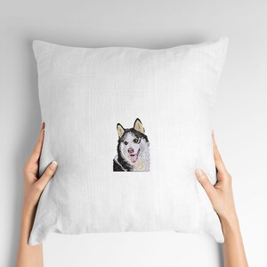 May include: White pillow with an embroidered image of a black and white husky dog with a pink tongue sticking out.