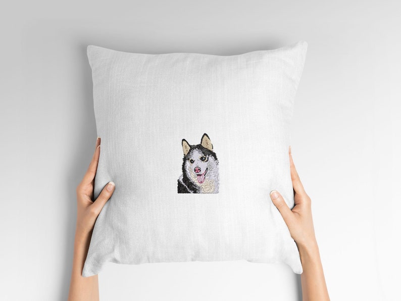 May include: White pillow with an embroidered image of a black and white husky dog with a pink tongue sticking out.