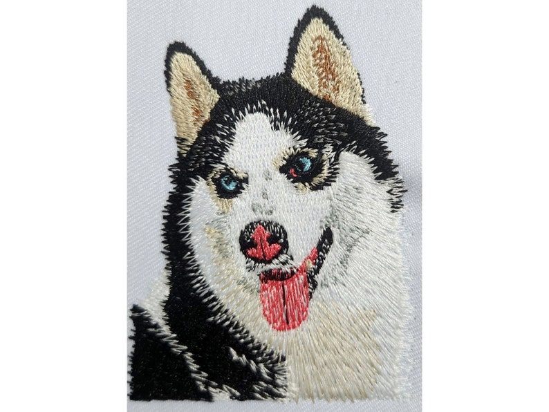May include: Close-up of an embroidered husky dog with blue eyes, a pink tongue, and black and white fur.